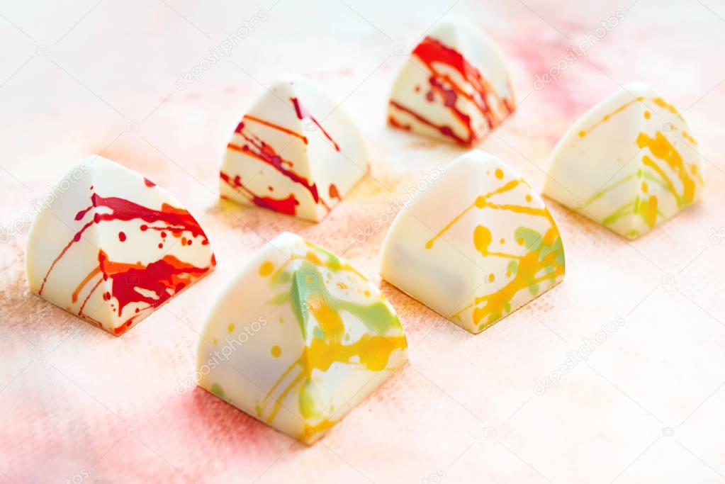 Unique handmade white chocolate sweets on abstract painting background