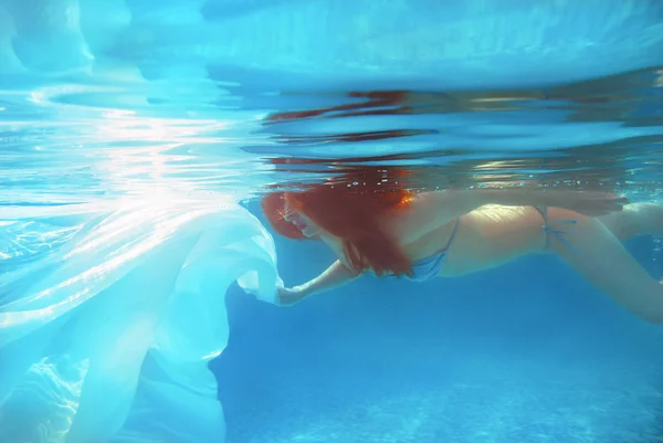 Portret van jonge mooie rode haren meisje onder water in het zwembad in de zomer met witte kleren — Stockfoto
