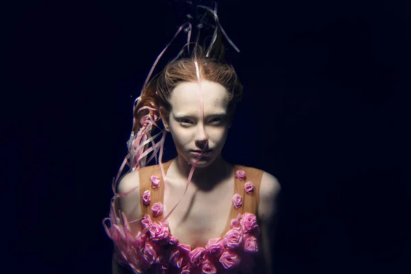 Portret van jonge mooie rode haren meisje in roze jurk en met rozen onderwater — Stockfoto