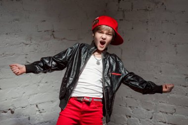 Portre serin genç hip hop çocuk kırmızı şapka ve kırmızı pantolon ve beyaz gömlek ve siyah deri ceket çatı