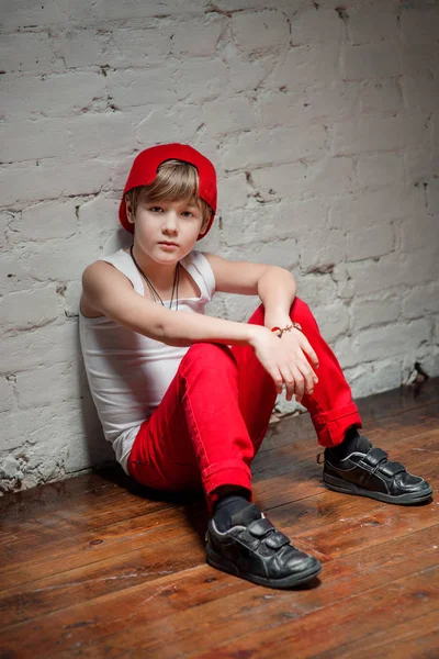 Портрет крутого молодого хлопчика хіп-хопу в червоному капелюсі і червоних штанях і білій сорочці в лофт — стокове фото