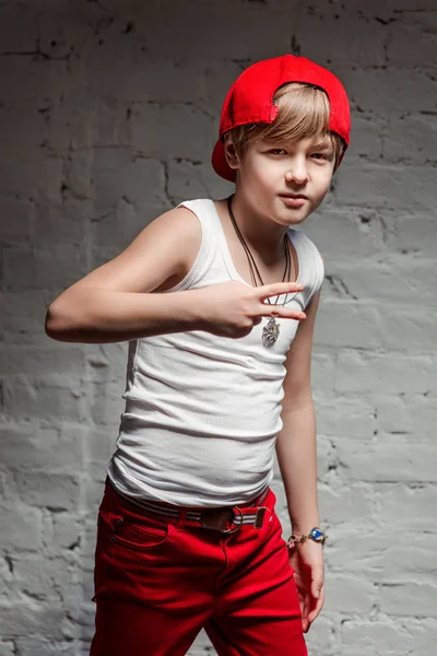 Portrait de jeune garçon hip hop cool en chapeau rouge et pantalon rouge et chemise blanche en loft — Photo