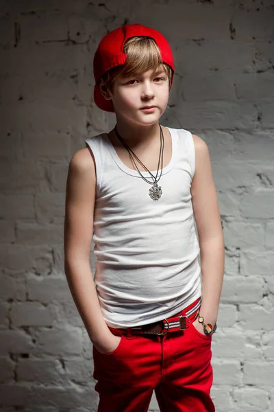 Портрет крутого молодого хлопчика хіп-хопу в червоному капелюсі і червоних штанях і білій сорочці на горищі — стокове фото
