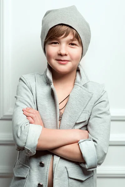 Портрет крутого молодого стильного хлопчика в сірому капелюсі і піджаку на світлому фоні — стокове фото