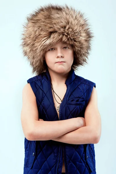 Портрет крутого молодого стильного хлопчика в хутряній шапці на світлому фоні — стокове фото