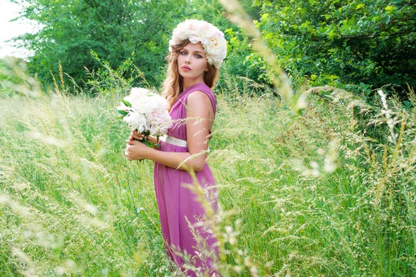 Portret de tânără frumoasă femeie creț în coroana de bujor în aer liber pe fundal verde — Fotografie, imagine de stoc