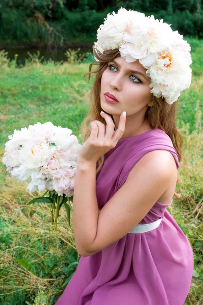 Portrait de jeune belle femme bouclée dans la couronne de pivoine en plein air sur fond vert — Photo