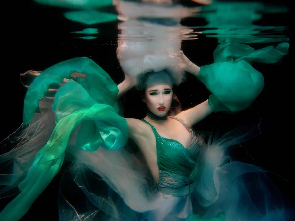 Ritratto della giovane bella ragazza in abito verde su sfondo nero sott'acqua in piscina — Foto Stock