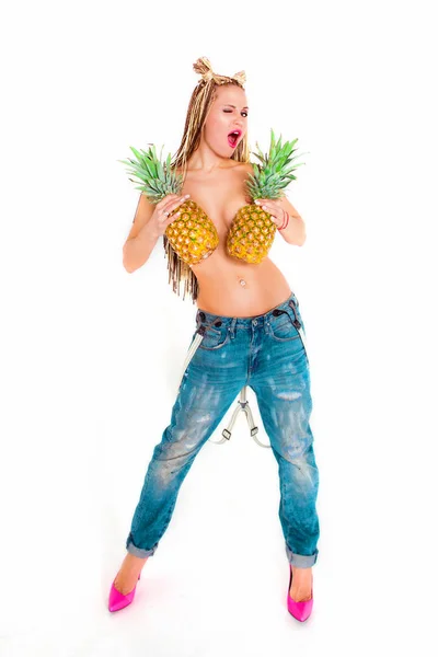Привлекательная молодая блондинка топлесс с пирсингом и африканскими косичками с ананасами в руках на красочном фоне — стоковое фото