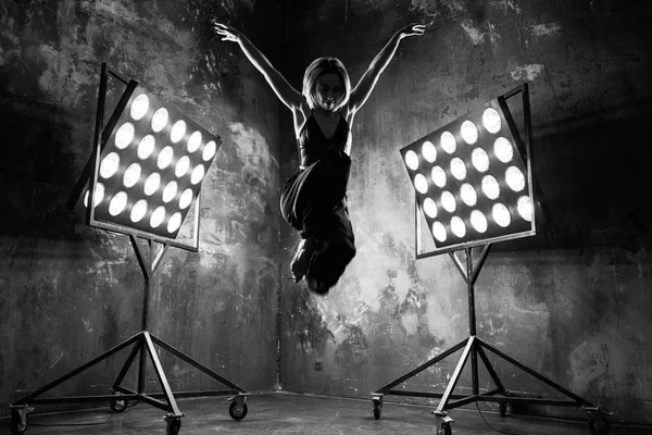 Retrato en blanco y negro de una hermosa y atractiva bailarina rubia en el escenario con luces en el fondo del loft bailando danza gratis —  Fotos de Stock