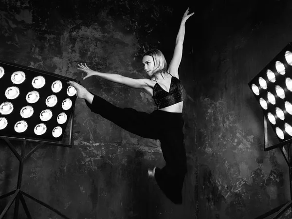 Svartvita porträtt av vackra attraktiv blond ung kvinna dansare på scenen med lampor i loft bakgrunden dansa fridans — Stockfoto