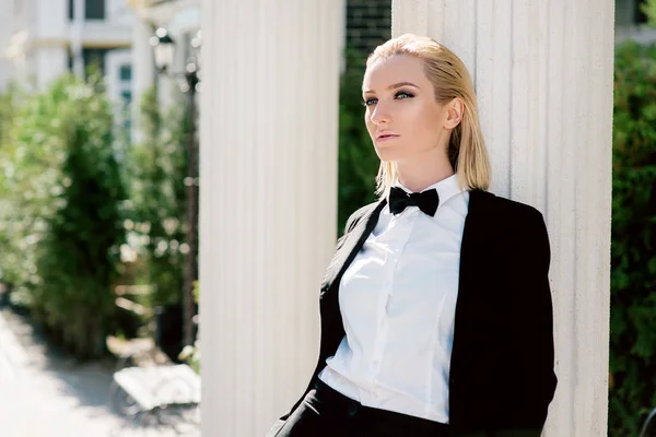 Retrato de mujer rubia hermosa de moda con estilo en traje negro hombre con corbata de lazo al aire libre — Foto de Stock