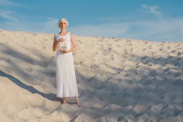 Joven mujer rubia hermosa en el desierto con peces de colores en sus manos — Foto de Stock