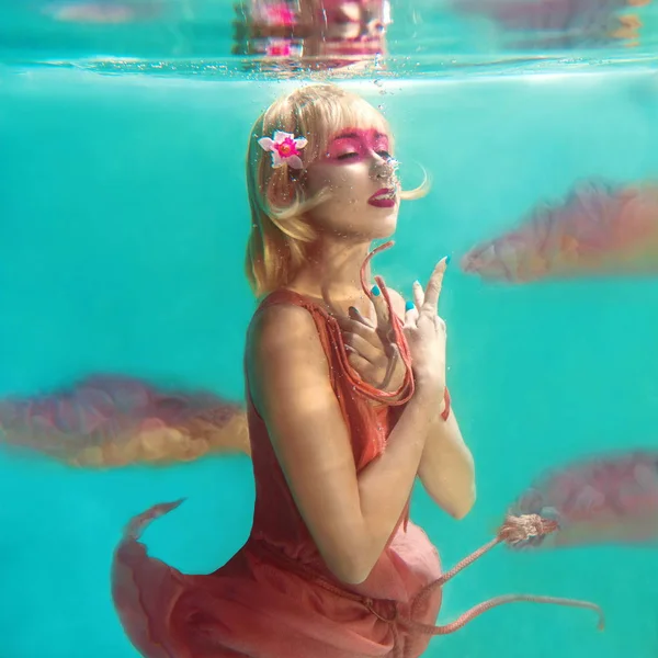 Портрет красивой блондинки с розовым фламинго под водой в бассейне — стоковое фото