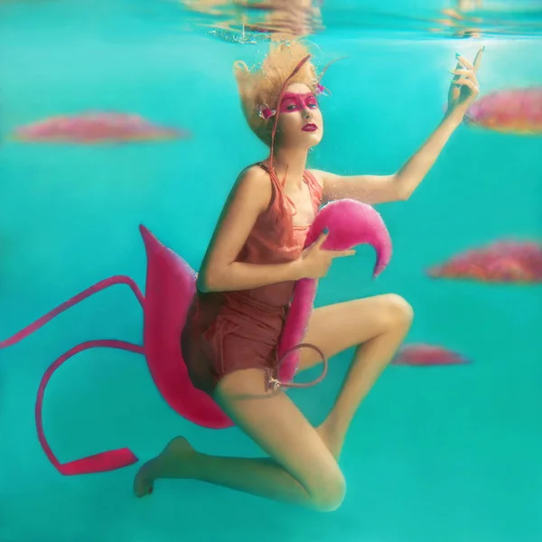 Portrait de belle femme blonde avec flamant rose volant sous l'eau dans la piscine — Photo