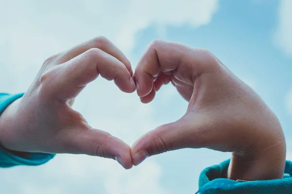 Mains de jeune fille faisant symbole de coeur sur le ciel — Photo