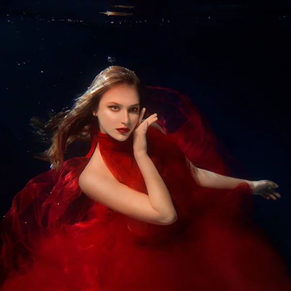 Retrato submarino ot joven hermosa chica con maquillaje en rojo elegante vestido en la piscina —  Fotos de Stock