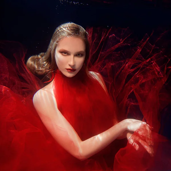 Sualtı portre ot genç yüzme havuzunda kırmızı şık elbiseli ile güzel kız makyaj — Stok fotoğraf