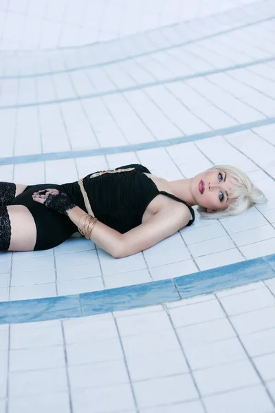 Bela jovem loira sensual mulher em roupa interior preta e meias sozinho na piscina vazia — Fotografia de Stock