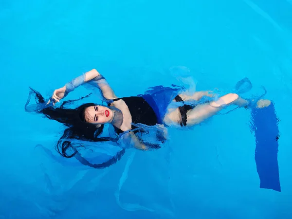 Schöne Darl Hair Frau im Kleid legt sich auf das Wasser im Schwimmbad — Stockfoto