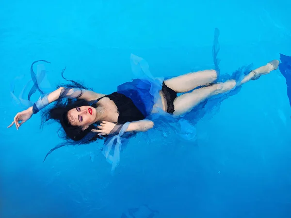 Belle femme de cheveux darl en robe couché sur l'eau dans la piscine — Photo