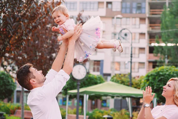 Счастливые молодые улыбающиеся родители с ребенком на свежем воздухе в парке — стоковое фото