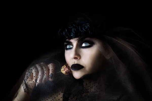 Темноволосая готическая девушка с черными губами и сухой розой в руке — стоковое фото