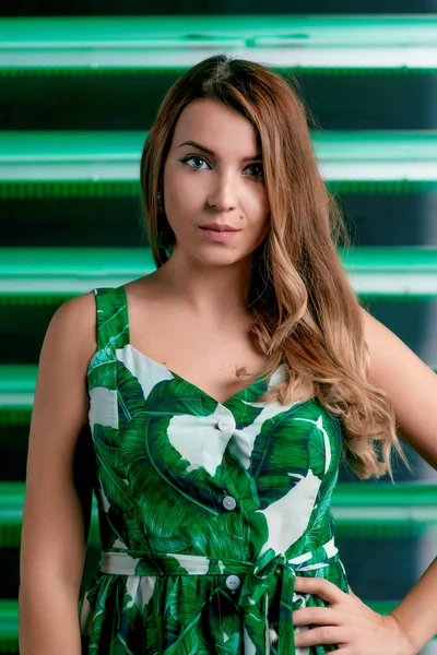 Portrait of stylish brown hair woman in green dress, green earrings, with makeup on green background in photostudio — Stock Photo, Image