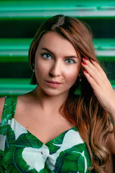 Portrait of stylish brown hair woman in green dress, green earrings, with makeup on green background in photostudio — Stock Photo, Image