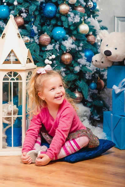 금발 소녀 거의 웃 고 앉아 크리스마스 트리 장식 — 스톡 사진