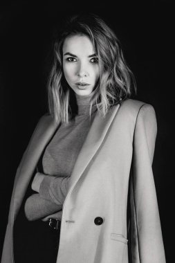 Siyah ve beyaz ceket, deri kıyafet, gaiters, koyu arka plan üzerinde patent ayakkabılar genç çekici güzel sarışın kadın portresi