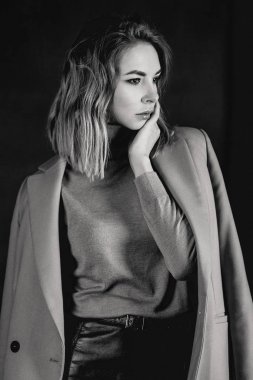 Siyah ve beyaz ceket, deri kıyafet, gaiters, koyu arka plan üzerinde patent ayakkabılar genç çekici güzel sarışın kadın portresi