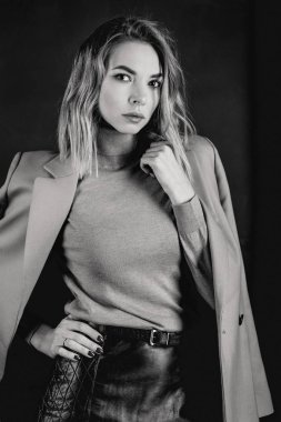 Siyah ve beyaz ceket, deri kıyafet, gaiters, koyu arka plan üzerinde patent ayakkabılar genç çekici güzel sarışın kadın portresi