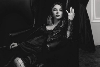 Siyah beyaz portre çekici şık sarışın genç kadın ipek elbise ve koltuk üzerinde siyah ceket