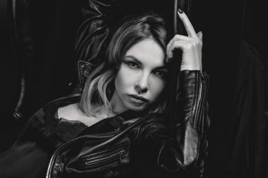 Siyah beyaz portre çekici şık sarışın genç kadın ipek elbise ve koltuk üzerinde siyah ceket