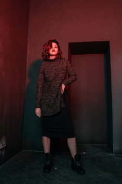 Karanlık odada gri süveterli dans eden güzel ihale kıvırcık kadın portresi