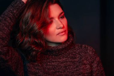 Güzel, kıvırcık, üzgün, depresif, gri kazaklı, karanlık odada yalnız bir kadının portresi.