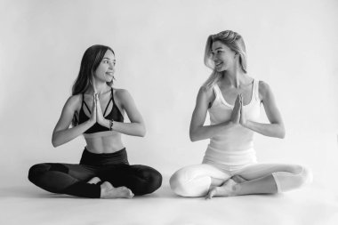 Sarışın ve esmer, güzel ve neşeli kadınların yoga asanlarını yaparken tek renkli portresi. Sağlıklı yaşam tarzı, Yin ve Yang ve spor konsepti