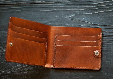 Deri el yapımı, siyah ahşap arka planda kahverengi, boş bir cüzdan. Finans, yoksulluk, para kavramı