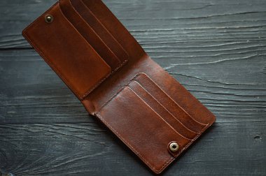 Deri el yapımı, siyah ahşap arka planda kahverengi, boş bir cüzdan. Finans, yoksulluk, para kavramı