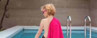 Fuşya ceketli, şık, kıvırcık saçlı, şık güneş gözlüklü ve yüzme havuzunun yanında siyah külotlu fevkalade bir kızın portresi. Moda, tarz, eğlence, eğlence, seyahat, makyaj konsepti. Film tahılı