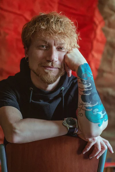 Portré Vörös Hajú Stílusos Férfi Tetoválással Kezén Széken Piros Háttér — Stock Fotó