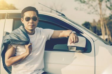 Başarılı genç adam arabanın yakınında ayakta.