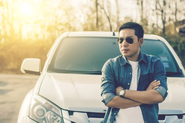 Başarılı genç adam arabanın yakınında ayakta.