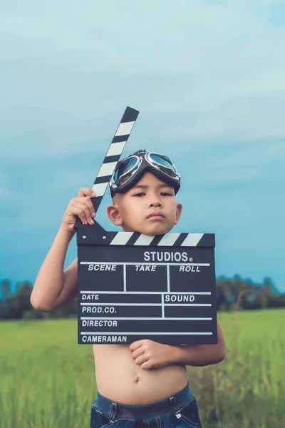 Kluk hraje filmové klapky Rady proti letní obloha pozadí. Fi — Stock fotografie