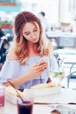 bir kafede otururken ve telefon uygulamada, güzel görünümlü güzel genç sarışın kadın fotoğraf seyahat reklam için dergiler için alışveriş, Foto - tarzı yaşam tarzı