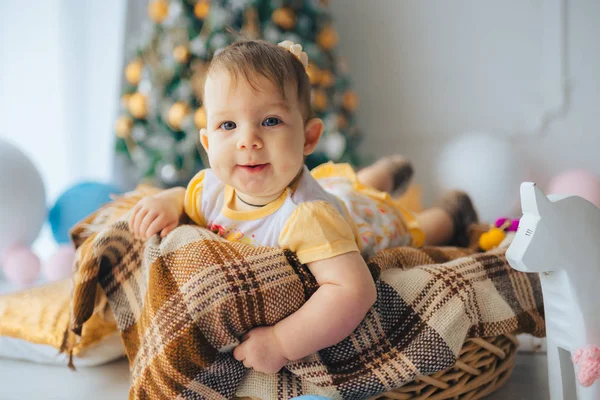 Komik giysileri bir Noel ağacı yakınındaki bir sepet içinde yalan ve yıldızlar ve topları kartopu için benzer şeklinde yastık çevrili küçük şirin kız