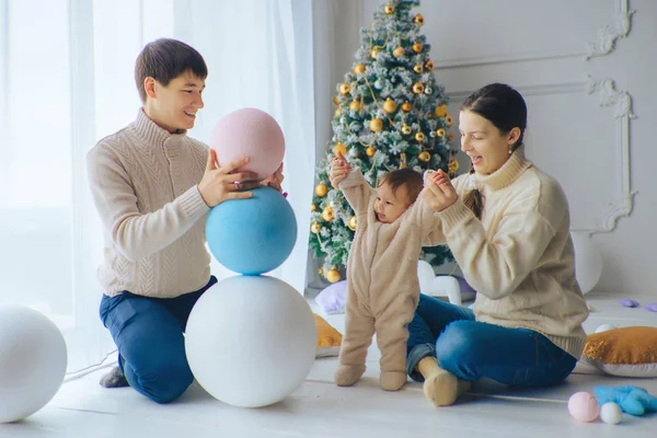 Genç ve güzel veliler bir küçük şirin kız Balls Noel ağacı (build a snowman yakınındaki kartopu gibi oynamak)