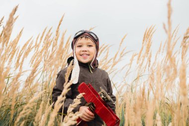 Çocuk gökyüzüne, hayal ve kırmızı bir uçak holding ararken uzun otların arasında duruyor
