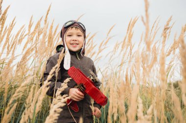 Çocuk gökyüzüne, hayal ve kırmızı bir uçak holding ararken uzun otların arasında duruyor